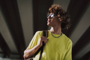 Siyah sırt çantası taşıyan gülümseyen kıvırcık genç adam