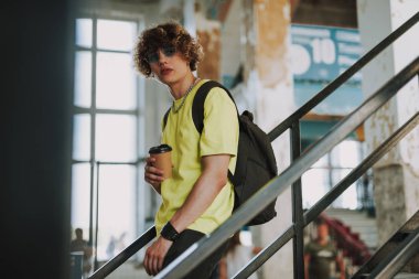 Aşağıda bir fincan kahve ile genç adam yürüyor