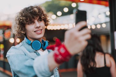 Gülümseyen kıvırcık adam akıllı telefon ile fotoğraf çekmek