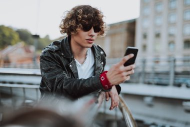 Köprüde akıllı telefon ile sakin kıvırcık adam