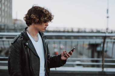 Genç bisikletçi akıllı telefonunu kullanarak köprüde