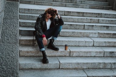 Kahve karton fincan ile taş merdivenlerde kıvırcık rocker