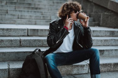 Akıllı telefonu olan adam kahve içip uzağa bakıyor