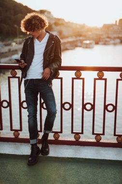 Banister yanında akıllı telefon ile genç rahat adam