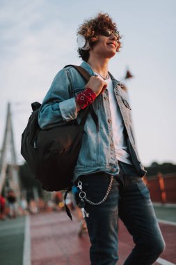 Sırt çantası ile yürüyen mutlu kıvırcık genç adam
