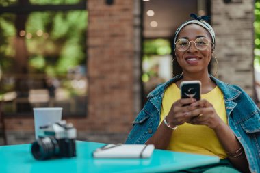 Kafe dışında akıllı telefon kullanarak Pretty afro-amerikan kadın