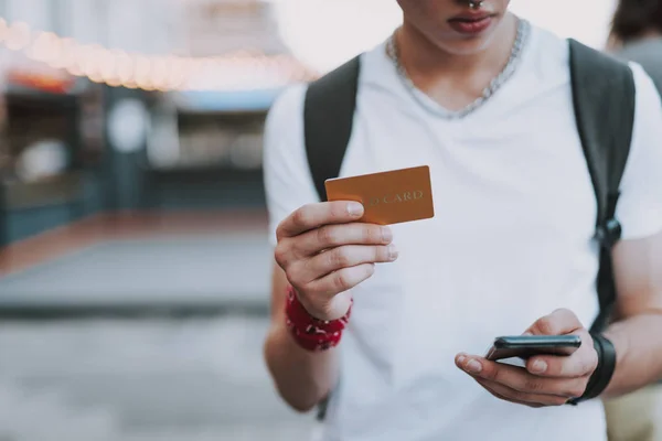 Estudante com smartphone furando cartão dourado pessoal — Fotografia de Stock