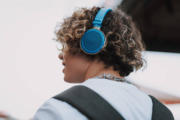 Ярко-голубые наушники на голове кудрявого человека
