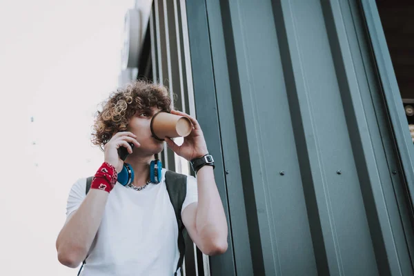 Estudiante rizado bebiendo café y hablando por teléfono — Foto de Stock