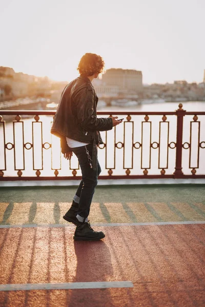 Lockiger junger Mann, der auf der Brücke läuft — Stockfoto