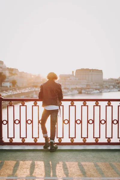 Lockiger junger Mann auf der Brücke in der Stadt — Stockfoto