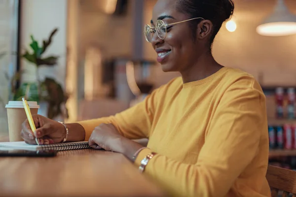 Young african american woman is writing notes — Stock Photo, Image
