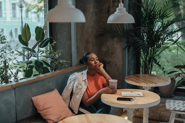 Молодая афро-американка сидит в кафе с напитками — стоковое фото