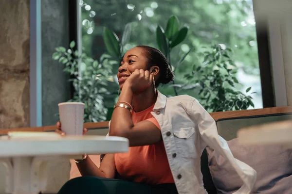 Giovane donna afro-americana sorridente e seduta nel caffè — Foto Stock