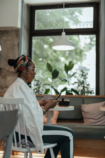 Gülümseyen genç afro-amerikalı bayan kafede oturan — Stok fotoğraf