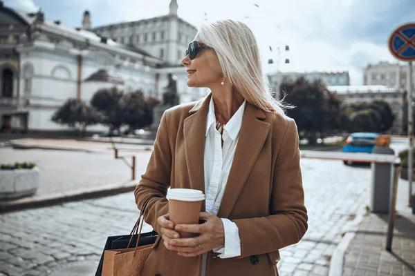 Улыбающаяся женщина с кофе на фотографии на улице — стоковое фото