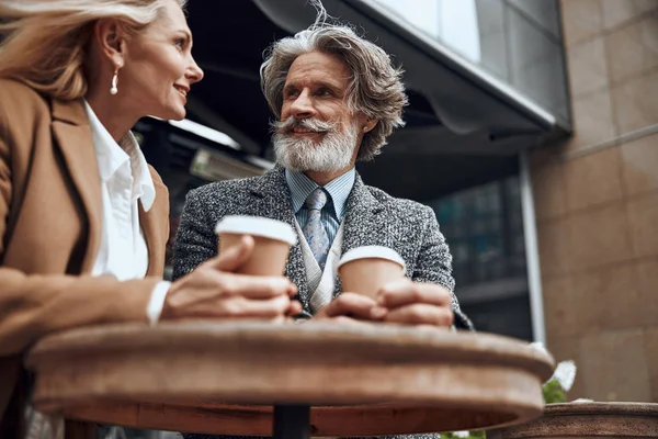 Зрелый мужчина с кофе улыбается женщине фото акции — стоковое фото