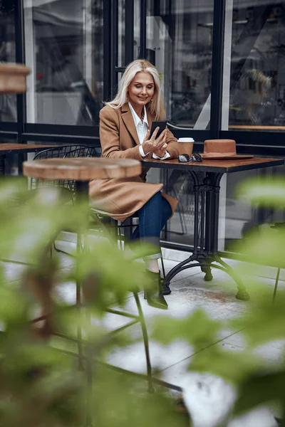 Felice donna utilizzando smartphone e sorridente stock foto — Foto Stock