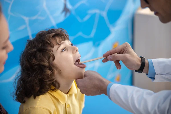 Il medico sta esaminando la gola del bambino in ufficio foto stock — Foto Stock