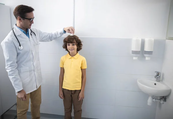Usmívající se pediatr se měří velikost akcií pro chlapce — Stock fotografie