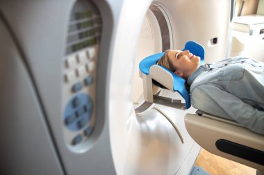 Radyoloji kliniğinde Ct masa üzerinde yatan gülümseyen genç kadın