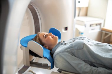 Radyoloji kliniğinde Ct tarayıcı masada yatan neşeli genç kadın