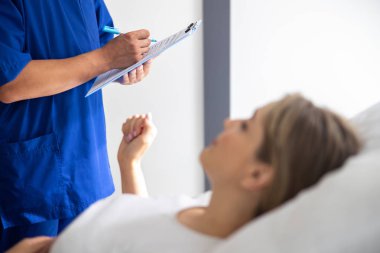 Hastayı ziyaret ederken tıbbi form dolduran doktor