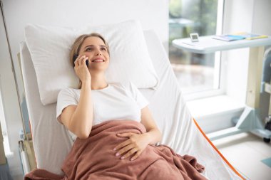 Hastane odasında telefon görüşmesi olan gülümseyen bayan
