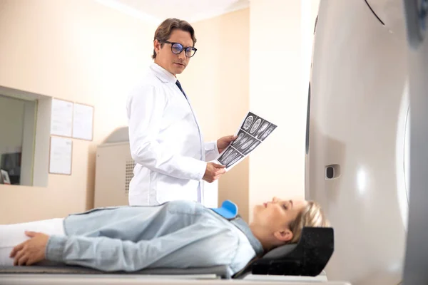 Лікар тримає КТ-сканування мозку і дивиться на жінку — стокове фото