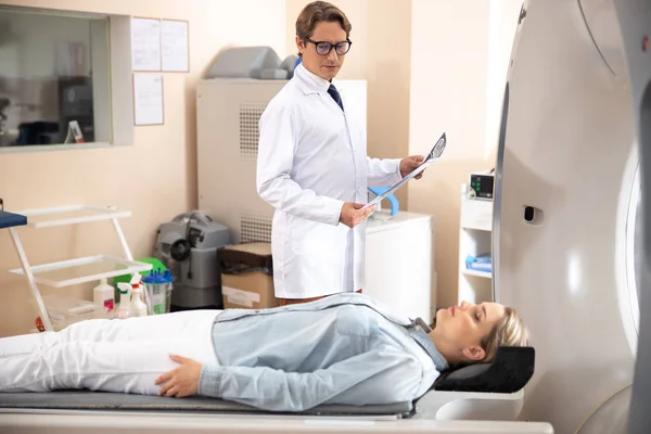 Лікар зі скануванням КТ мозку, дивлячись на пацієнта — стокове фото