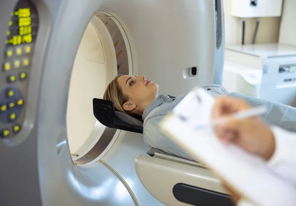 Young woman lying on CT machine table at radiology clinic — Stock Photo, Image