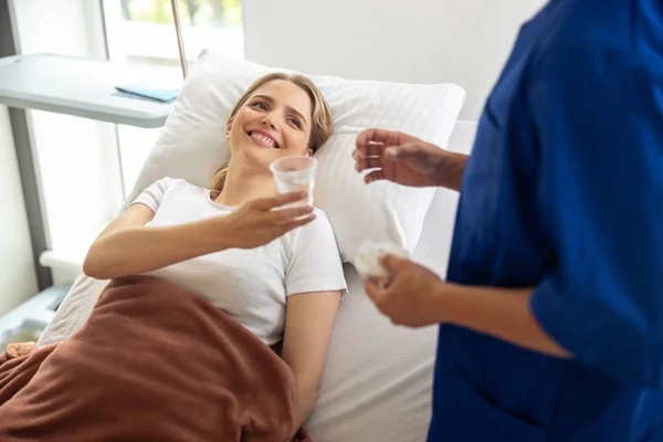 Lachende dame houden kopje water en kijken naar dokter — Stockfoto