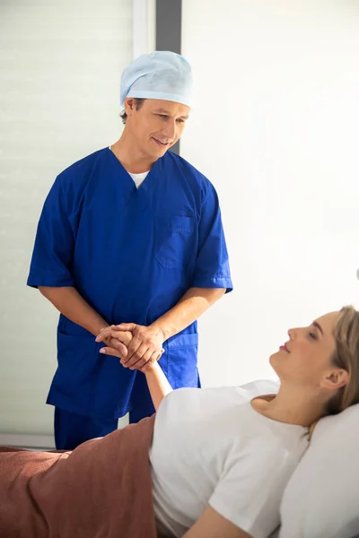 Doctor Holding hand van jonge dame in ziekenhuis kamer — Stockfoto