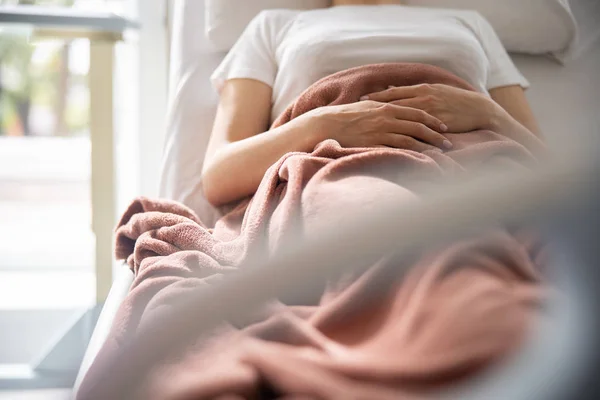 Giovane donna con le braccia sulla pancia che riposa nella stanza d'ospedale — Foto Stock