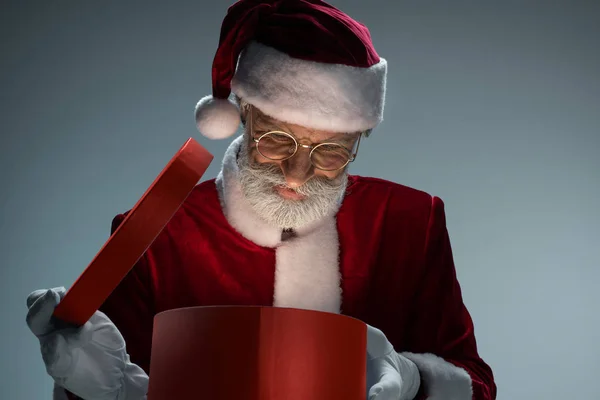 Yaşlı Noel Baba açık hediye kutusu bakıyor — Stok fotoğraf