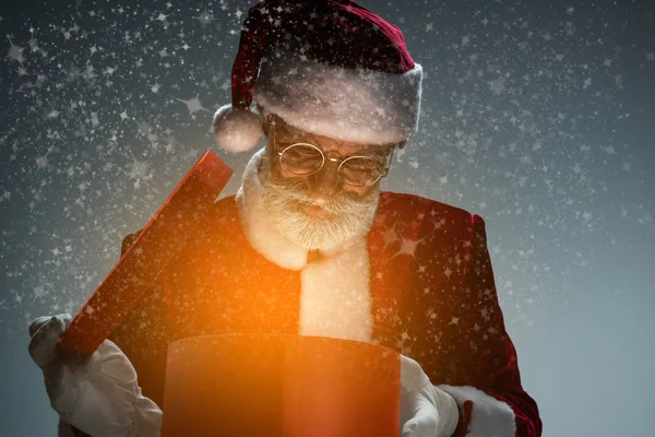 Père Noël regardant boîte cadeau avec la lumière — Photo