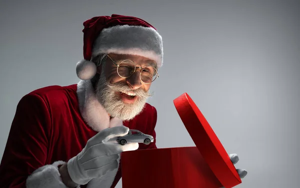Starszy Święty Mikołaj pakowania samochodu wewnątrz otwartego pudełka — Zdjęcie stockowe