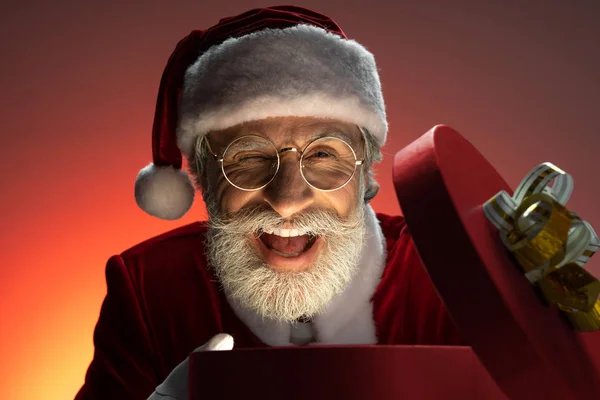 Старший Санта-Клаус с открытой коробкой подарков в руках — стоковое фото