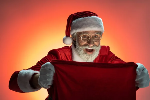 Mature Père Noël regardant à l'intérieur sac avec des cadeaux — Photo