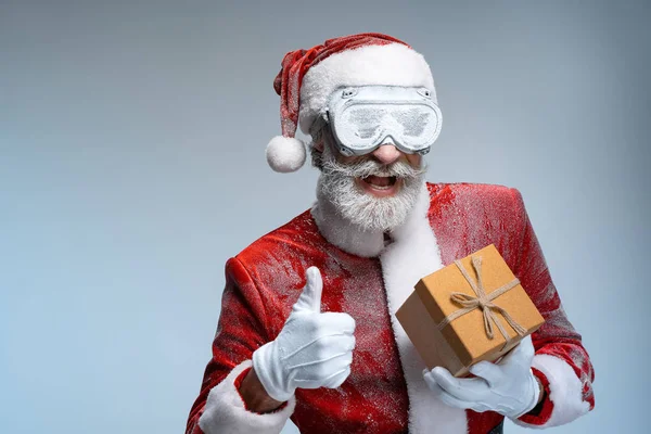 Santa Claus holding christmas present, showing thumbs up — Stock Photo, Image