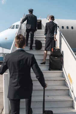 Olgun Kafkas pilotlar ve uçuş görevlisi uçak merdivenine çıkıyor