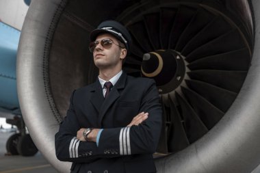 Ciddi genç adam uçağın motoru yakınında duruyor