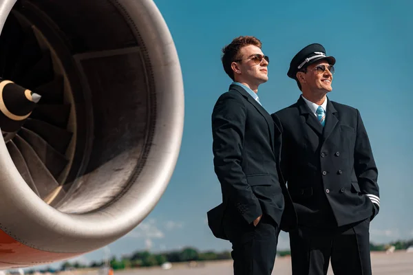 Attraktive erwachsene Kollegen stehen in der Nähe des Flugzeugmotors im Freien — Stockfoto