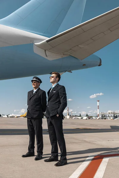 Vuxna män i uniform poserar för kamera i flygplatsen — Stockfoto