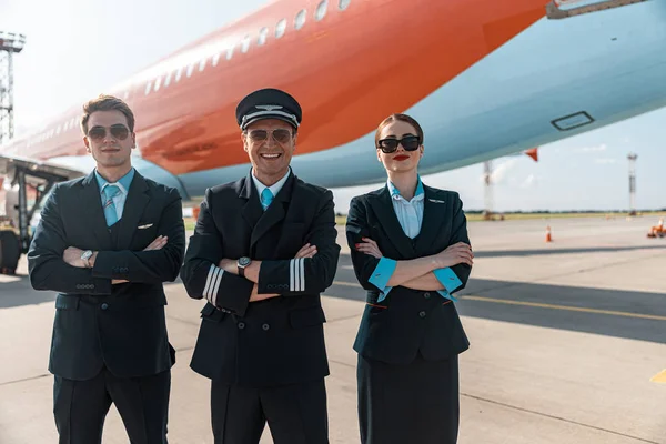 Felice squadra equipaggio amichevole sta sorridendo sotto vicino aereo — Foto Stock