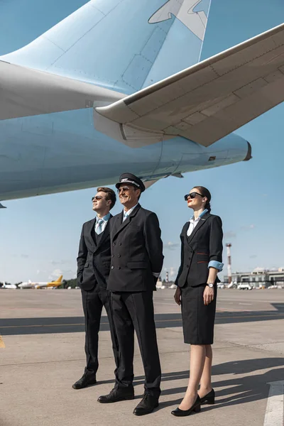 Glückliches Crew-Team steht unter Flugzeugflügel — Stockfoto