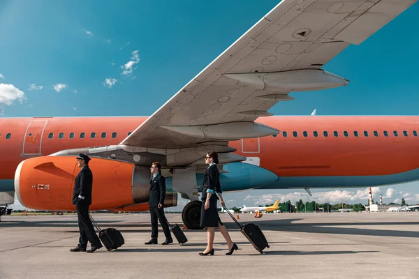 Pilotos caucásicos y auxiliares de vuelo caminando en el aeropuerto —  Fotos de Stock