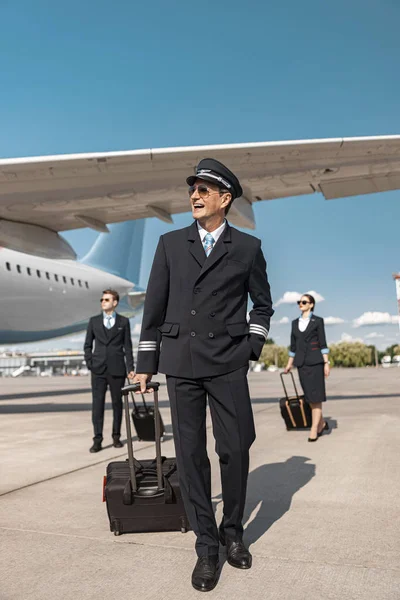 Aantrekkelijke Kaukasische piloot met koffer wandelen in de luchthaven — Stockfoto