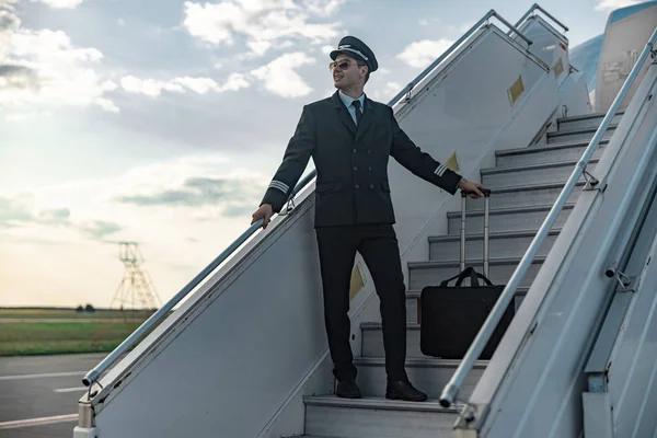 身着制服的有吸引力的飞行员站在飞机梯子上 — 图库照片