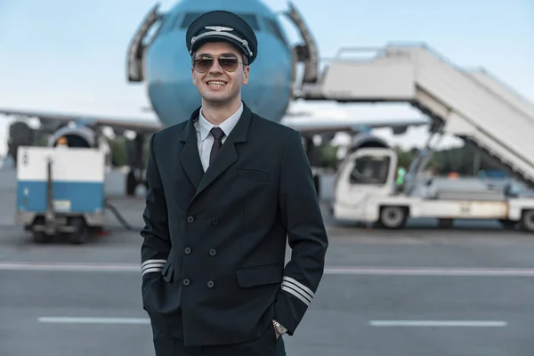 Красивый улыбающийся пилот в форме, гуляющий в аэропорту — стоковое фото